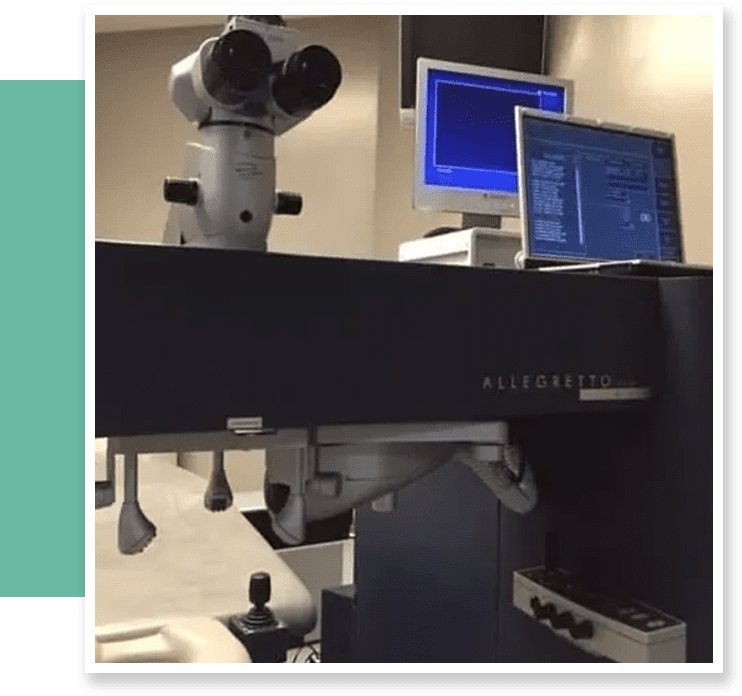 A picture of an office with two monitors and a microscope.